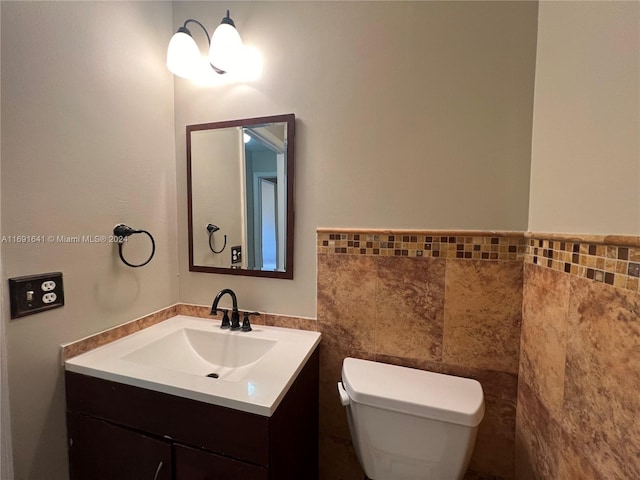 bathroom featuring vanity, toilet, and tile walls