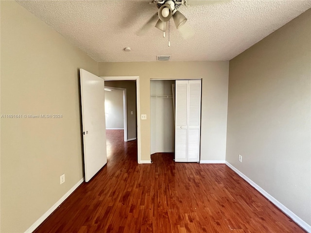 unfurnished bedroom with a textured ceiling, dark wood-type flooring, ceiling fan, and a closet