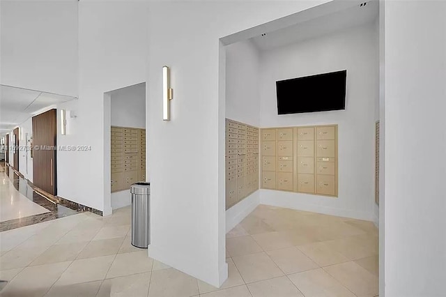 corridor featuring light tile patterned flooring, a high ceiling, and mail boxes