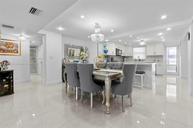 dining area featuring a chandelier, sink, and light tile patterned flooring