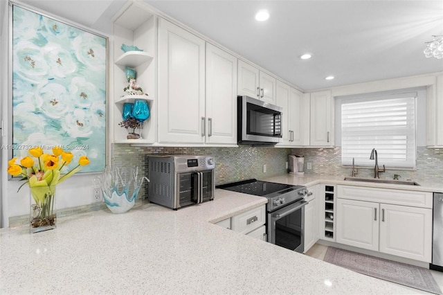 kitchen with appliances with stainless steel finishes, sink, light stone counters, and white cabinets