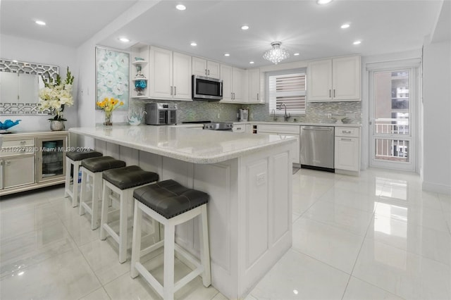 kitchen with stainless steel appliances, white cabinetry, backsplash, a breakfast bar, and kitchen peninsula