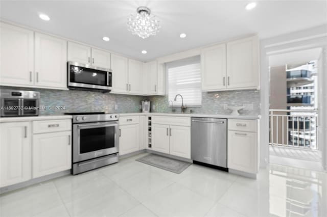 kitchen featuring stainless steel appliances, white cabinets, light tile patterned floors, and tasteful backsplash