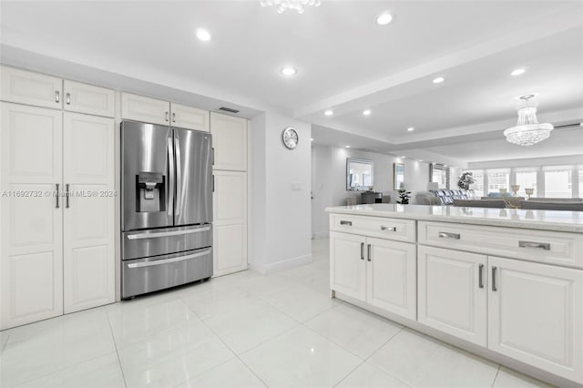 kitchen featuring white cabinets, stainless steel refrigerator with ice dispenser, light tile patterned floors, and an inviting chandelier