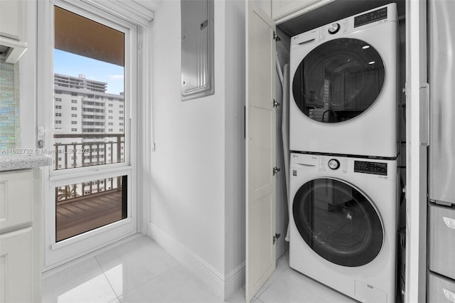 washroom featuring electric panel, light tile patterned floors, and stacked washer and clothes dryer