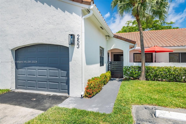 view of exterior entry featuring a garage and a lawn