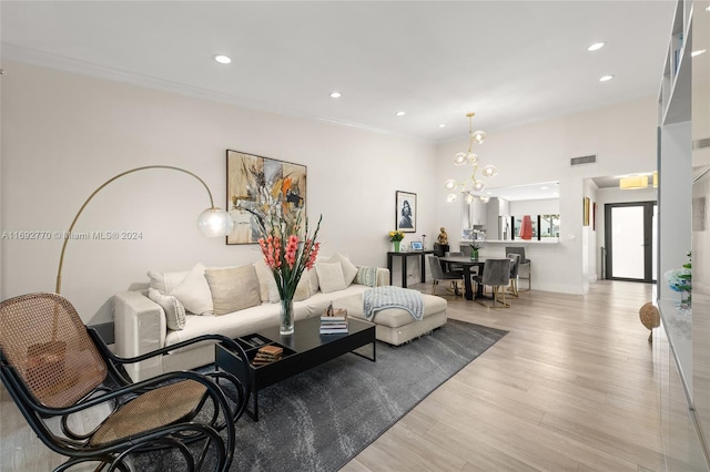 living room featuring light hardwood / wood-style floors, a chandelier, and crown molding