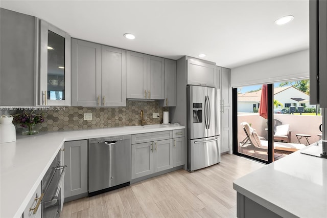 kitchen featuring gray cabinetry, sink, light hardwood / wood-style flooring, and appliances with stainless steel finishes