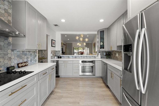 kitchen featuring light hardwood / wood-style floors, beverage cooler, gray cabinets, wall chimney range hood, and appliances with stainless steel finishes