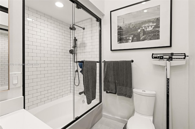 bathroom with tile patterned flooring, shower / bath combination with glass door, and toilet