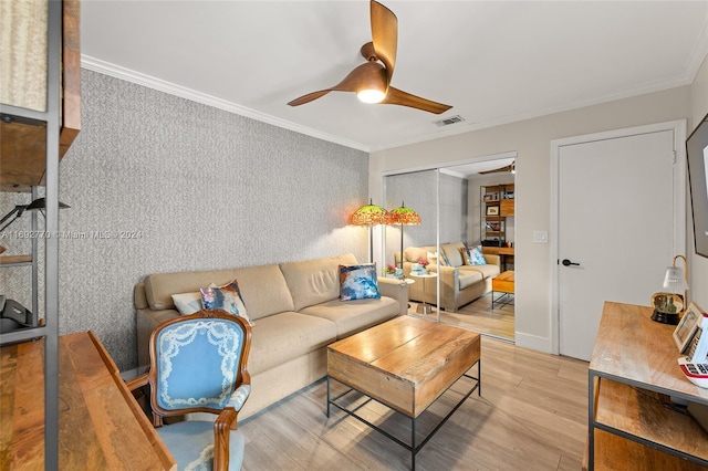 living room with ornamental molding, light wood-type flooring, and ceiling fan