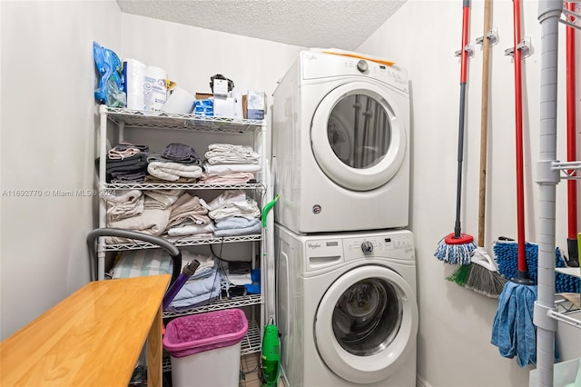 washroom featuring stacked washing maching and dryer and a textured ceiling