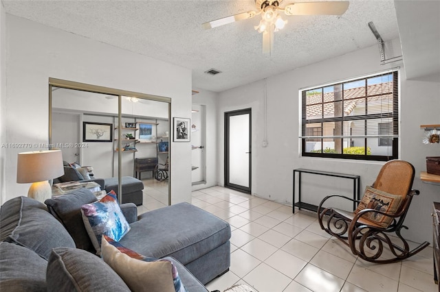 living room with ceiling fan, a textured ceiling, and light tile patterned floors