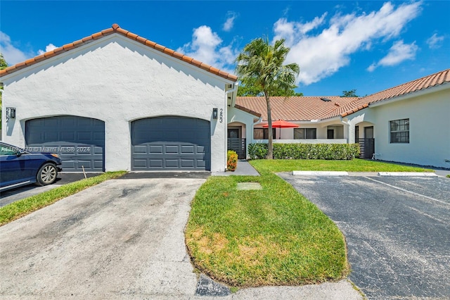 mediterranean / spanish-style house featuring a garage and a front lawn