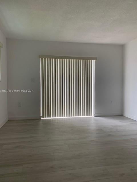 unfurnished room with a textured ceiling, light hardwood / wood-style floors, and a healthy amount of sunlight