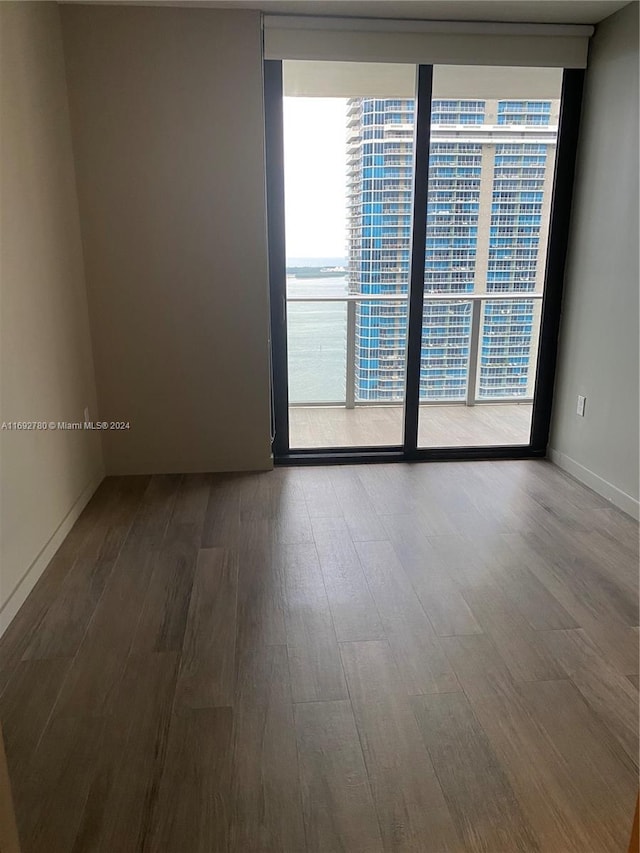 empty room featuring a water view, hardwood / wood-style flooring, and floor to ceiling windows