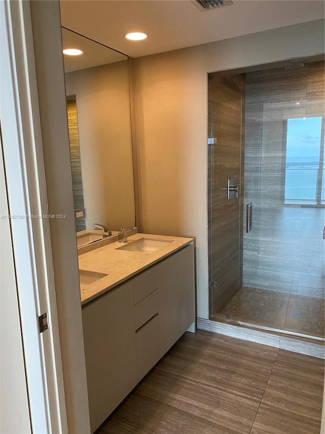 bathroom with an enclosed shower, vanity, and wood-type flooring