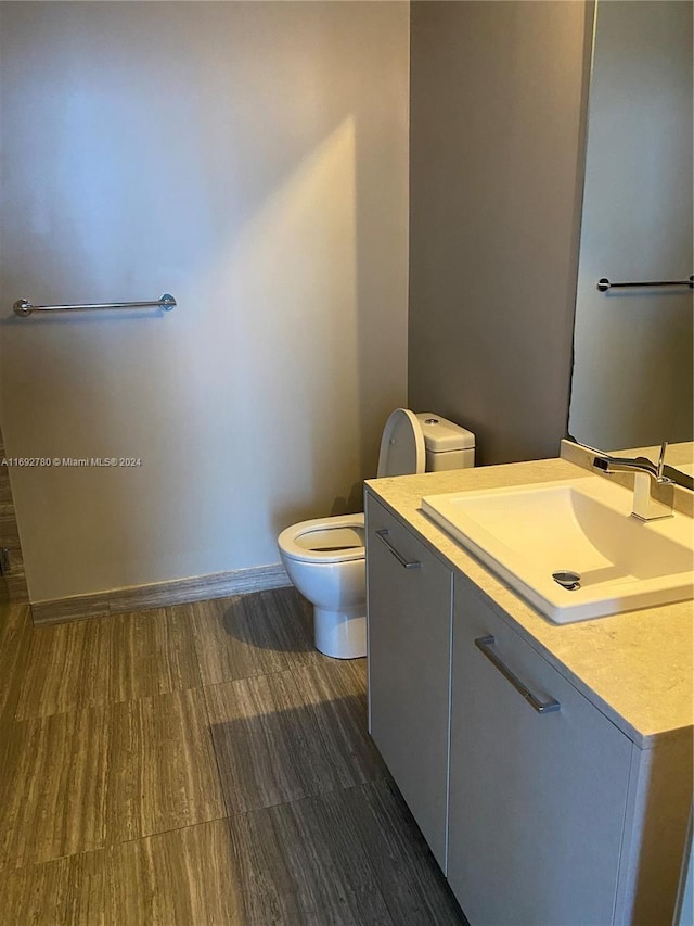 bathroom with vanity, toilet, and wood-type flooring