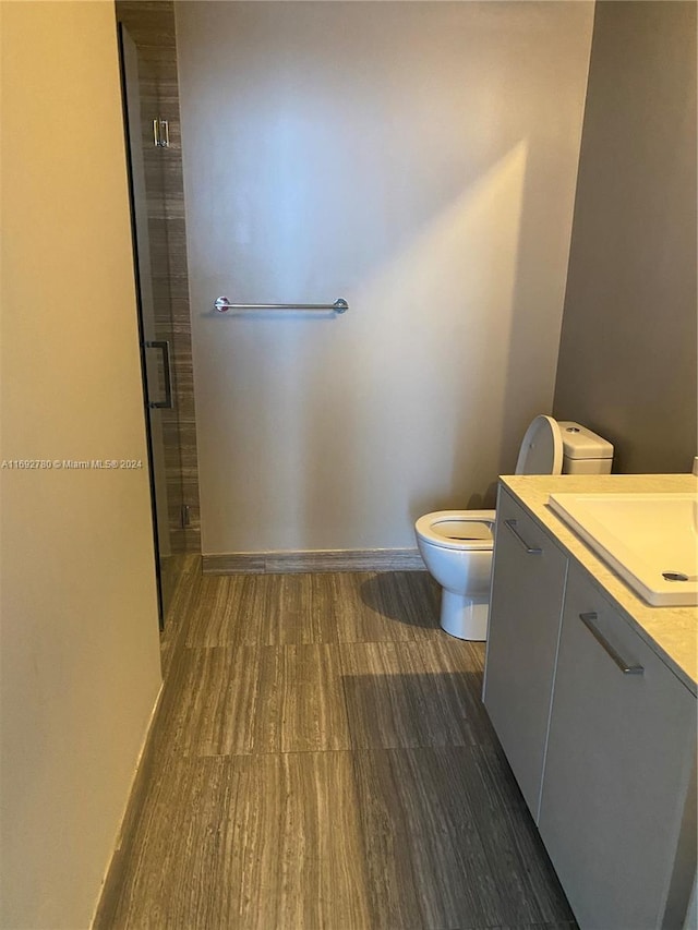 bathroom with vanity, hardwood / wood-style flooring, toilet, and a shower with shower door