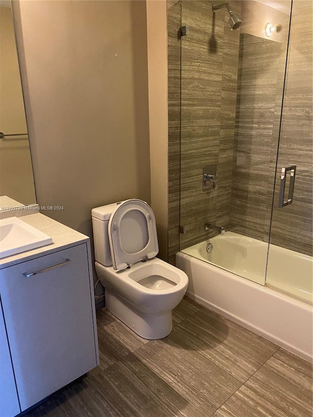 full bathroom featuring toilet, combined bath / shower with glass door, and vanity