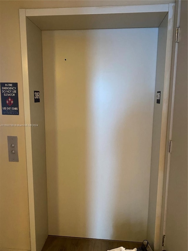 hallway with elevator and wood-type flooring