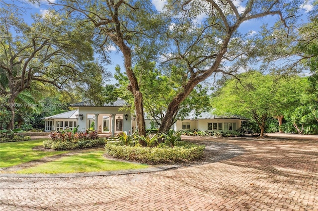 view of front facade with stucco siding, decorative driveway, and a front yard