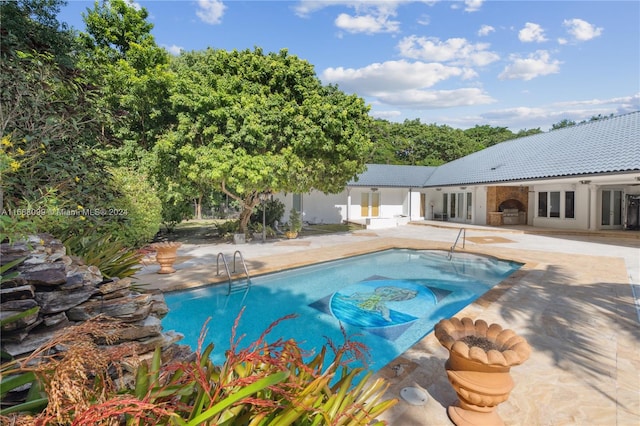 view of swimming pool with exterior fireplace and a patio