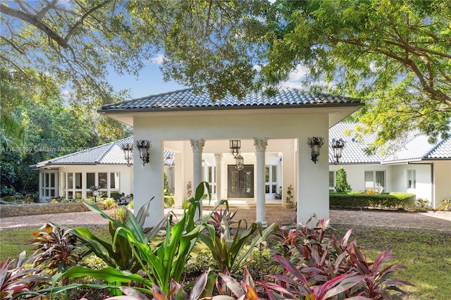 rear view of property featuring stucco siding and a tiled roof