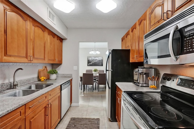 kitchen with a textured ceiling, stainless steel appliances, light tile patterned flooring, and washer and dryer