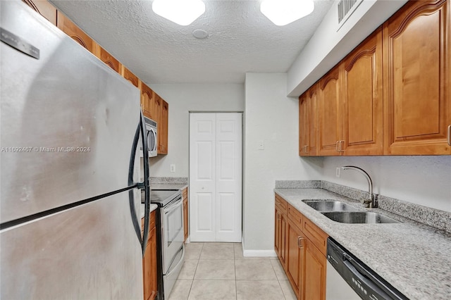 kitchen featuring stainless steel appliances, a textured ceiling, sink, and light tile patterned floors