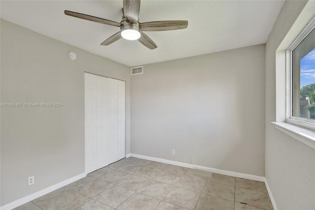 spare room with ceiling fan and light tile patterned floors