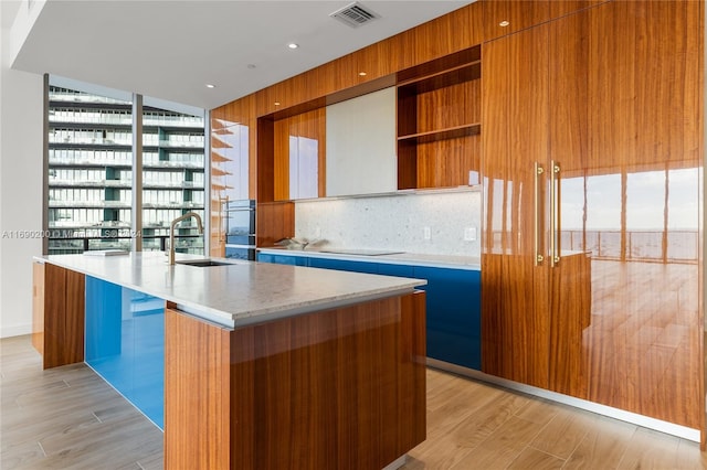 kitchen featuring a wealth of natural light, sink, an island with sink, and light hardwood / wood-style flooring