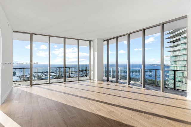 interior space featuring expansive windows, a water view, baseboards, and wood finished floors