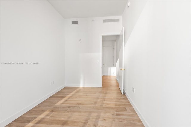 empty room with light wood-style flooring, baseboards, and visible vents