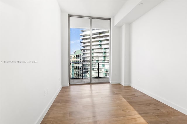 unfurnished room featuring expansive windows, light hardwood / wood-style flooring, and a wealth of natural light