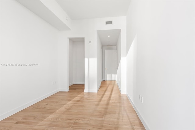 hall featuring visible vents, baseboards, and light wood-style floors