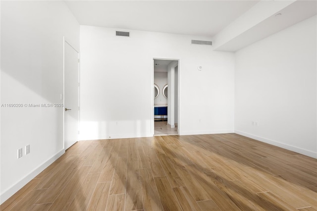 unfurnished room with wood finished floors, visible vents, and baseboards