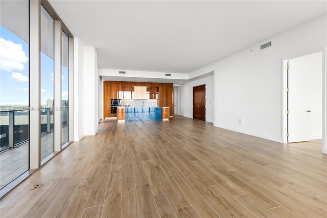 unfurnished living room featuring light hardwood / wood-style flooring and a wall of windows