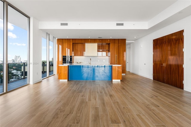 kitchen with oven, decorative backsplash, light wood-type flooring, and sink