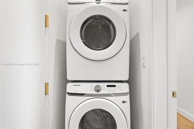 laundry area with hardwood / wood-style floors and stacked washer / drying machine