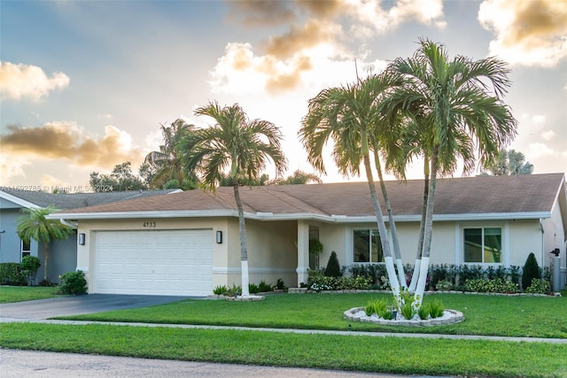 single story home featuring a garage and a yard