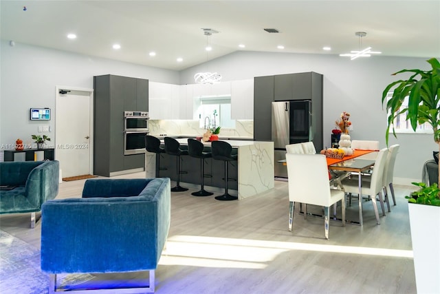 interior space with light hardwood / wood-style floors, an inviting chandelier, and lofted ceiling