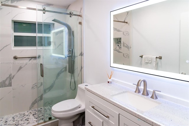 bathroom featuring vanity, toilet, and a shower with door