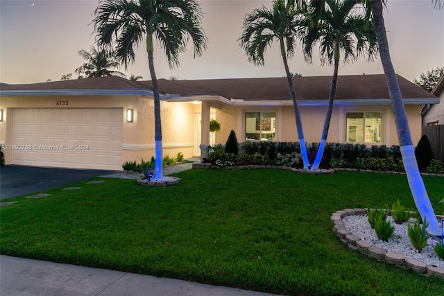 single story home featuring a garage and a yard