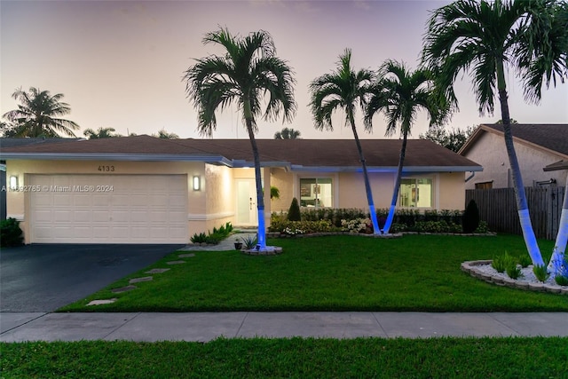 ranch-style house featuring a garage and a lawn