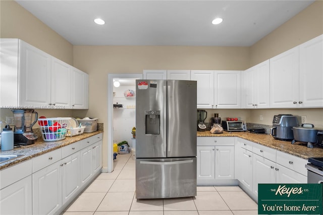 kitchen featuring light stone counters, white cabinets, light tile patterned flooring, and stainless steel refrigerator with ice dispenser