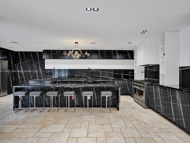 kitchen featuring white cabinets, a kitchen breakfast bar, tile walls, and high end stainless steel range