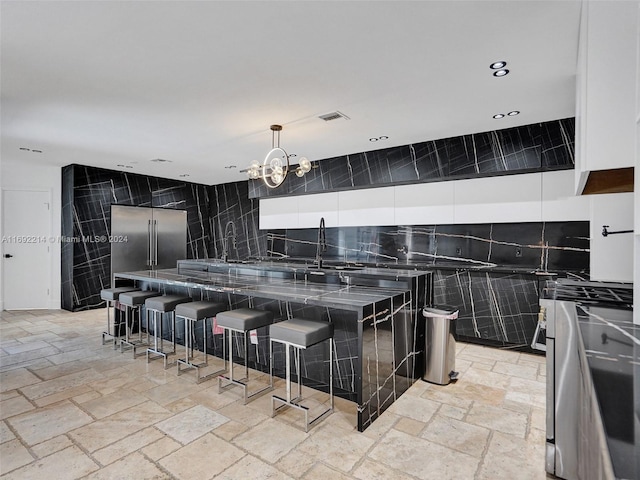 kitchen featuring backsplash, a notable chandelier, a kitchen bar, and tile walls