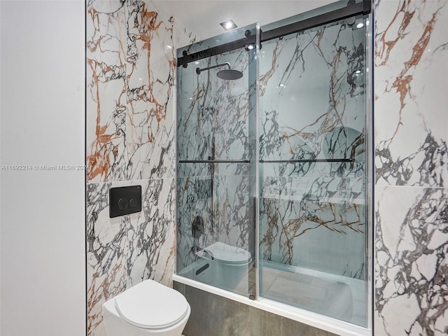 bathroom featuring tiled shower / bath combo, toilet, and tile walls