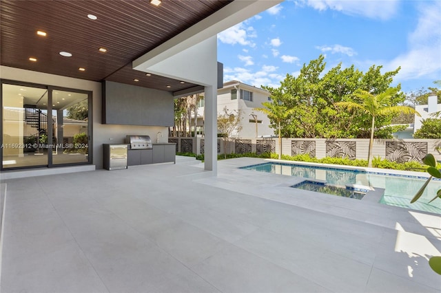 view of pool with an outdoor kitchen, a grill, and a patio